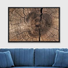 a blue couch sitting in front of a wooden wall with a tree stump pattern on it