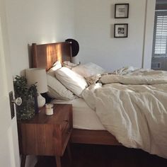 an unmade bed in a bedroom with white sheets and blankets on it's headboard