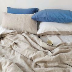 an unmade bed with two pillows and a book on the bottom shelf next to it