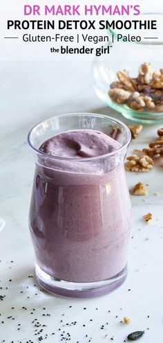 a smoothie in a glass next to some granola and other ingredients on a table