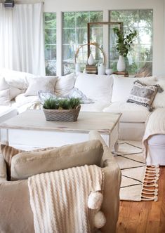 a living room filled with white furniture and lots of pillows on top of it's couches