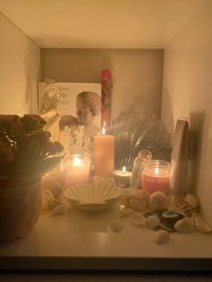 candles are lit on a table with shells and seashells