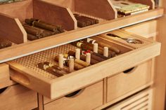 an open drawer with several cigars and other items in it on top of wooden drawers