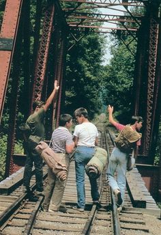 several people walking across a bridge with their arms in the air