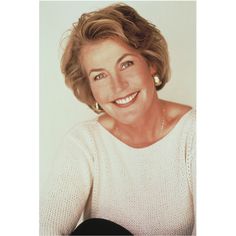 an older woman with blonde hair and white sweater smiling at the camera while holding a black guitar