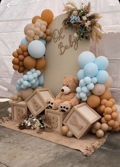 a teddy bear surrounded by balloons and other items for a baby's first birthday