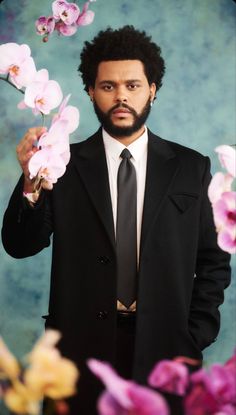 a man wearing a suit and tie holding flowers in front of his face with both hands