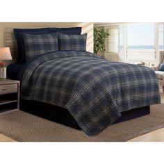 a bed in a room with a blue plaid comforter