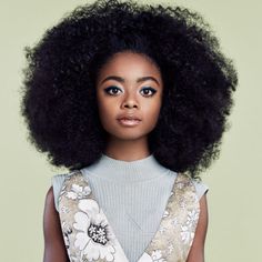 a young woman with an afro standing in front of a green background