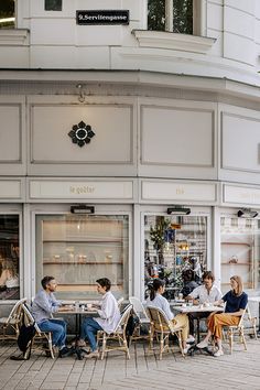 people sitting at tables in front of a building