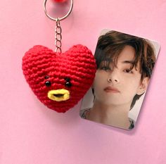 a red knitted heart shaped keychain next to a photo of a person's face