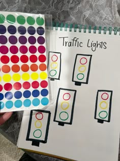 a person holding up a traffic light sticker next to a notebook with the words traffic lights on it