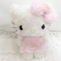 a white hello kitty stuffed animal sitting on top of a bed