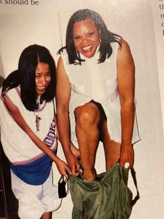 an image of two women that are posing for a picture together in front of a magazine