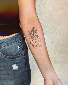 a woman with a tattoo on her arm holding a flower in one hand and a heart in the other