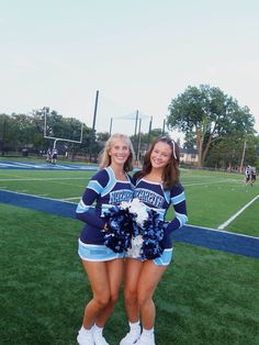 two cheerleaders pose for a photo on the field