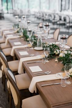 a long table set with place settings and flowers on the top, along with empty wine glasses