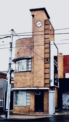 a tall brick building with a clock on it's side in front of power lines