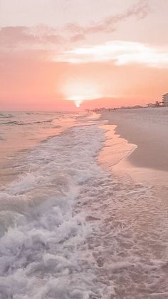 the sun is setting at the beach with waves coming in