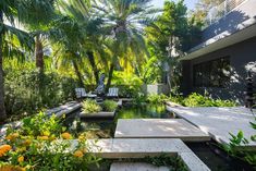 an outdoor garden with plants and water features in the foreground, surrounded by palm trees