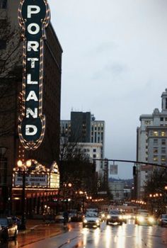 a city street filled with lots of traffic next to tall buildings covered in christmas lights