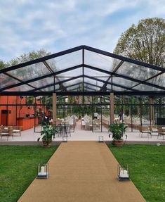 a walkway leading to a glass walled building with tables and chairs in the back ground