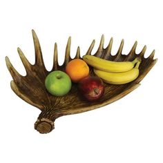 a wooden bowl filled with fruit on top of a white table next to an antler's tail