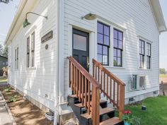 a small white house with stairs leading up to the front door