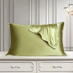 a green pillow on top of a white dresser