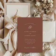 the wedding stationery is laid out on a bed of silks and paper flowers