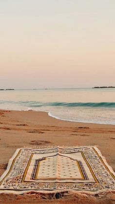 a blanket is laying on the beach near the water's edge with an ocean in the background