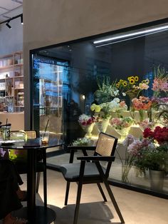 a woman sitting at a table in front of a flower shop