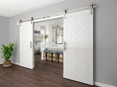 an open door leading to a kitchen and dining room with white walls, wood floors and wooden flooring