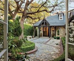 an open door leading to a house with a stone walkway and garden area in front