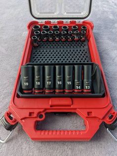 an open tool box filled with lots of black screwdrivers on top of a gray surface