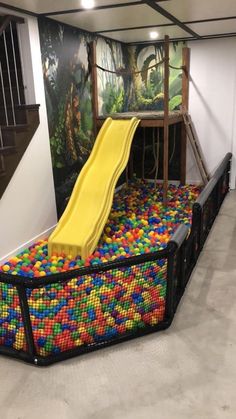 an indoor play area with colorful balls and a yellow slide