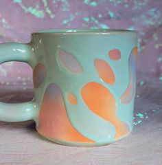 a close up of a coffee cup on a table with pink and blue glitters