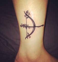 a tattoo on the foot of a woman with an arrow and leaves in it,