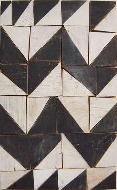 several black and white tiles are arranged in the shape of an abstract pattern on wood