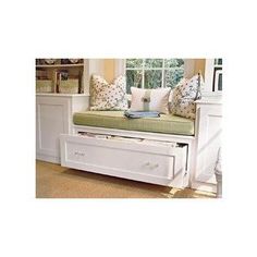 a white bench with drawers underneath it in front of a window and bookshelf