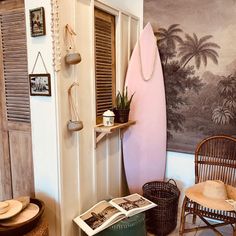 a pink surfboard sitting on top of a wooden shelf next to a chair and table