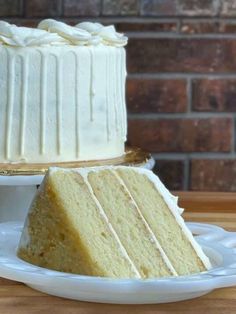 a white cake sitting on top of a wooden table next to a slice of cake