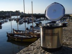 a large pot sitting on top of a rock next to a river filled with boats