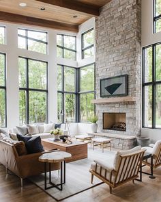 a living room filled with lots of windows and furniture next to a fire place on top of a hard wood floor