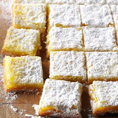 several pieces of cake sitting on top of a wooden cutting board with powdered sugar