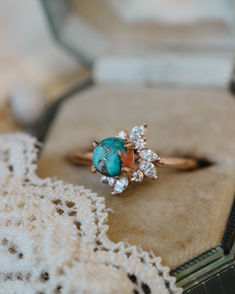 A close up image showing the "Aurae" engagement ring from Staghead Designs. This 14K rose gold ring features asymmetrical floral diamond accents made up of marquise and round diamonds around a round cabochon cut spiny oyster turquoise. Spiny oyster turquoise is a composite stone made up of turquoise, pyrite, and orange spiny oyster shell. Western Engagement Rings, Turquoise And Diamond Ring, Western Wedding Rings, Turquoise Engagement Ring, Turquoise Wedding Rings, Turquoise Wedding Band, Turquoise Ring Engagement, Spiny Oyster Turquoise, Aqua Wedding