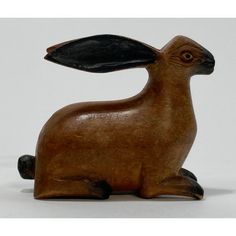 a wooden rabbit figurine sitting on top of a white table next to a black object