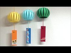 three colorful hot air balloons hanging from hooks on a wall with tags attached to them