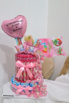 a birthday cake made out of candy and candies with a heart balloon on top