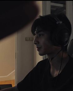 a young man wearing headphones sitting in front of a computer screen with his hand on the keyboard